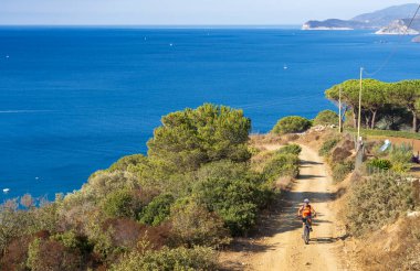 İtalya Toskana Takımadası 'ndaki Elba Adası' nda Akdeniz kıyısında elektrikli dağ bisikletine binen hoş bir kadın.