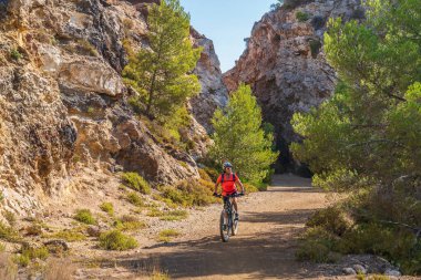 Elba, Toskana Takımadaları, Toskana, İtalya 'daki terk edilmiş Calamite Yarımadası' nda elektrikli dağ bisikletine binen güzel bir kadın.