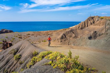 Elba, Toskana Takımadaları, Toskana, İtalya 'daki terk edilmiş Calamite Yarımadası' nda elektrikli dağ bisikletine binen güzel bir kadın.