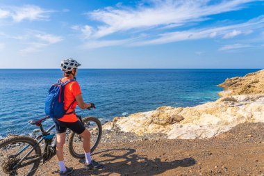 İtalya Toskana Takımadası 'ndaki Elba Adası' nda Akdeniz kıyısında elektrikli dağ bisikletine binen hoş bir kadın.