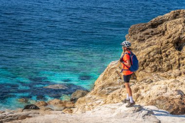 İtalya Toskana Takımadası 'ndaki Elba Adası' nda Akdeniz kıyısında elektrikli dağ bisikletine binen hoş bir kadın.