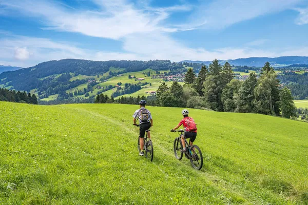 nice and remained young grandmother and her grandson riding their electrc mountain bikes in the Allgaeu Alps near Oberstaufen in Bavaria, Germany