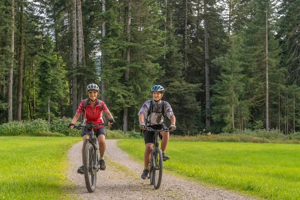 nice and remained young grandmother and her grandson riding their electrc mountain bikes in the Allgaeu Alps near Oberstaufen in Bavaria, Germany