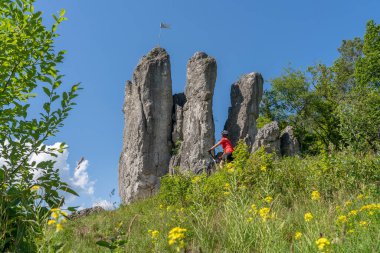 Franconian İsviçre 'de kayalık bir patikada elektrikli dağ bisikleti üzerinde ilerleyen güzel yaşlı kadın, ünlü kaya tepelerine, Ağaç tepelerine, Bavyera' ya, Almanya 'ya hayran.
