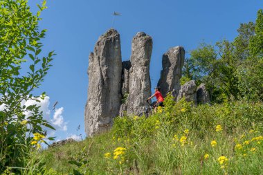 Franconian İsviçre 'de kayalık bir patikada elektrikli dağ bisikleti üzerinde ilerleyen güzel yaşlı kadın, ünlü kaya tepelerine, Ağaç tepelerine, Bavyera' ya, Almanya 'ya hayran.