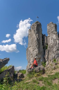 Franconian İsviçre 'de kayalık bir patikada, elektrikli dağ bisikleti üzerinde dinlenen yaşlı güzel bir kadın, ünlü kaya tepelerine hayran, Ağaç tepeleri, Bavyera, Almanya