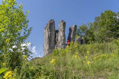 Franconian İsviçre 'de kayalık bir patikada elektrikli dağ bisikleti üzerinde ilerleyen güzel yaşlı kadın, ünlü kaya tepelerine, Ağaç tepelerine, Bavyera' ya, Almanya 'ya hayran.