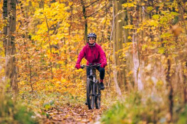 Stuttgart yakınlarındaki sonbahar ormanı patikalarında bisiklete binen hoş, son sınıf öğrencisi bir kadın. Güzel sıcak renkler, Baden-Wuerttemberg, Almanya.