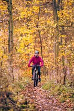 Stuttgart yakınlarındaki sonbahar ormanı patikalarında bisiklete binen hoş, son sınıf öğrencisi bir kadın. Güzel sıcak renkler, Baden-Wuerttemberg, Almanya.