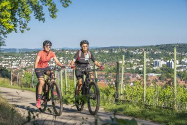 Büyükanne ve torun dağ bisikletlerine biniyor ve güneşli bir öğleden sonra Almanya 'nın Baden-Wuerttemberg kenti Stuttgart' ın yukarısındaki üzüm bağlarında eğleniyorlar.