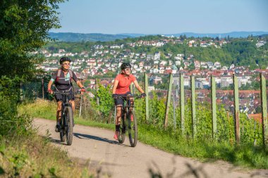 Büyükanne ve torun dağ bisikletlerine biniyor ve güneşli bir öğleden sonra Almanya 'nın Baden-Wuerttemberg kenti Stuttgart' ın yukarısındaki üzüm bağlarında eğleniyorlar.