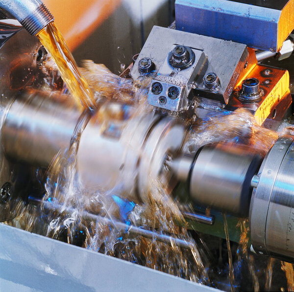 Milling machine with coolant in motion, processing a car piston