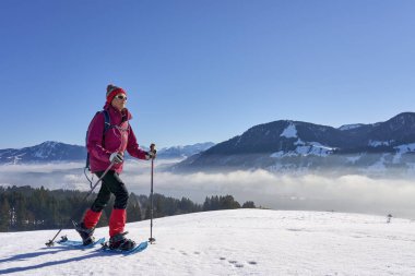  Almanya, Bavyera, Immenstadt 'ın yukarısındaki Allgau Alplerinde kar ayakkabısı giyen hoş ve aktif bir son sınıf öğrencisi.                             