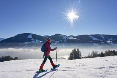   Almanya, Bavyera, Immenstadt 'ın yukarısındaki Allgau Alplerinde kar ayakkabısı giyen hoş ve aktif bir son sınıf öğrencisi.                             