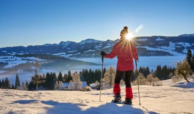   Almanya, Bavyera, Immenstadt 'ın yukarısındaki Allgau Alplerinde kar ayakkabısı giyen hoş ve aktif bir son sınıf öğrencisi.                             
