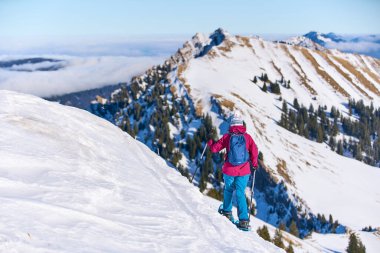     Bregenz Wald dağlarının, Hochgrat 'ın, Steibis' in, Bavyera Alpleri 'nin, Almanya' nın üzerindeki sis denizinin üzerinde Nagelfluh zincirinde kar ayakkabısı giyen son sınıf güzeli bir kadın.                           