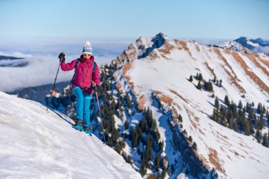     Bregenz Wald dağlarının, Hochgrat 'ın, Steibis' in, Bavyera Alpleri 'nin, Almanya' nın üzerindeki sis denizinin üzerinde Nagelfluh zincirinde kar ayakkabısı giyen son sınıf güzeli bir kadın.                           