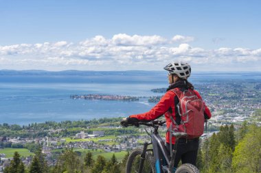 Oberstaufen yakınlarındaki Allgaeu Alplerinde elektrikli dağ bisikletine binen siluet gibi bir kadın. Bregenz Wald Dağları, Vorarlberg, Avusturya