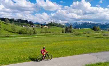 İlkbaharın başlarında Oberstaufen yakınlarındaki Allgau dağlarında elektrikli dağ bisikletine binen orta yaşlı güzel bir kadın Hochgrat, Nagelfluh zinciri, Bavyera, Almanya