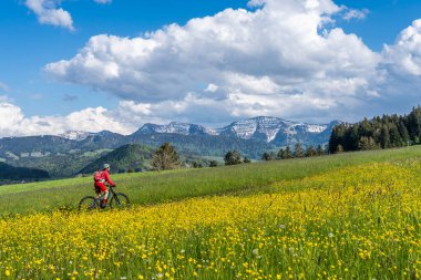 İlkbaharın başlarında Oberstaufen yakınlarındaki Allgau dağlarında elektrikli dağ bisikletine binen orta yaşlı güzel bir kadın Hochgrat, Nagelfluh zinciri, Bavyera, Almanya