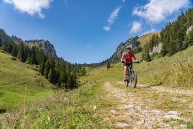 Avusturya 'nın Vorarlberg kentindeki Bregenzer Wald dağ sırasındaki Winterstaude zirvesinin aşağısındaki Schreiber Sattel' e elektrikli dağ bisikletiyle giden son sınıf öğrencisi hoş bir kadın.