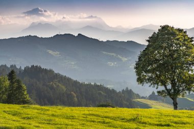 Aktif bir kadın gün batımında elektrikli dağ bisikletini sürüyor Saentis Dağı 'nın muhteşem siluetinin önünde, Appenzell Switthe
