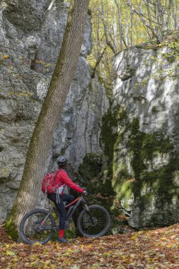 Swabian Alb, Baden Wuerttemberg, Almanya 'da renkli bir sonbahar ormanında elektrikli dağ bisikletine binen son sınıf öğrencisi hoş bir kadın.