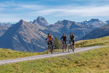 Avusturya, Vorarlberg, Mellau yakınlarındaki Bregenz Wald dağlarının sonbahar atmosferinde dağ bisikletlerine binen üç mutlu yetişkin.