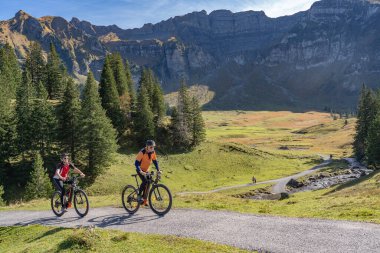Avusturya, Vorarlberg, Mellau yakınlarındaki Bregenz Wald dağlarının sonbahar atmosferinde dağ bisikletlerine binen üç mutlu yetişkin.