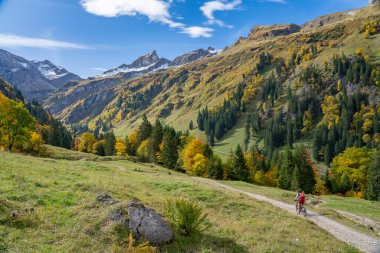 Hindeland, Bavyera, Almanya yakınlarındaki Allgau dağlarının sonbahar atmosferinde elektrikli dağ bisikleti süren aktif son sınıf öğrencisi bir kadın.