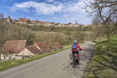 Rothenburg ob der Tauber, Franconia, Bavyera, Almanya 'nın ortaçağ siluetinin altındaki ünlü Alman şatolarında bisiklet turunda olan güzel bir şehir kadını.
