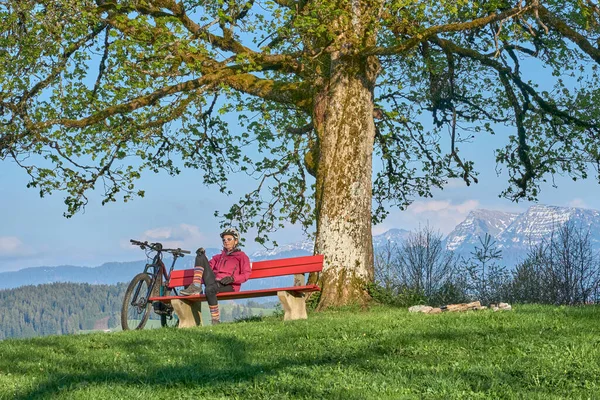 Almanya 'nın Bavyera, Oberstaufen yakınlarındaki Allgau Dağları' nda bahar aylarında bisiklet turunda mola veren son sınıf güzeli bir kadın.