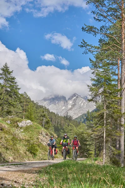 group of three active seniors riding Their  electric mountain bikes in the Lech Valley mountains near Reutte in Tirol, Austria