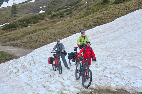 Group Three Active Seniors Riding Electric Mountain Bikes Crossing Snow — Φωτογραφία Αρχείου