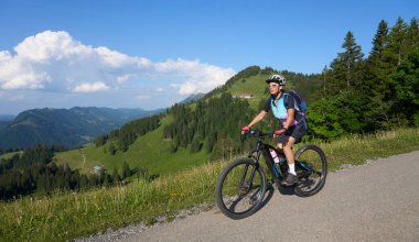 Allgau Alpleri, Bavyera Almanya 'daki Nagelfluh dağ zinciriyle Oberstaufen' in yukarısındaki dağlarda elektrikli dağ bisikletine binen son sınıf güzel bir kadın.