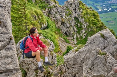 nice senior woman hiking at Mount Gruenten in the Allgaeu Alps with awesomw view over Iller valley and the Allgaeu low lands, Bavaria, Germany