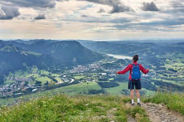 nice senior woman hiking at Mount Gruenten in the Allgaeu Alps with awesomw view over Iller valley to Lake Alpsee and Lake of Constanz, Bodensee, Bavaria, Germany