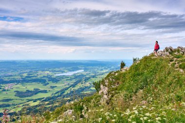 nice senior woman hiking at Mount Gruenten in the Allgaeu Alps with awesomw view over Iller valley and the Allgaeu low lands, Bavaria, Germany