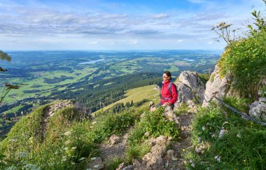 nice senior woman hiking at Mount Gruenten in the Allgaeu Alps with awesomw view over Iller valley and the Allgaeu low lands, Bavaria, Germany