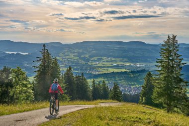 nice active senior woman riding her electric mountain bike at Mount Gruenten in the Allgaeu Alps , Bavaria, Germany