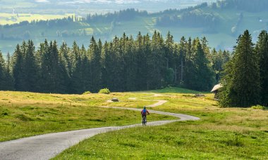 nice active senior woman riding her electric mountain bike at Mount Gruenten in the Allgaeu Alps , Bavaria, Germany