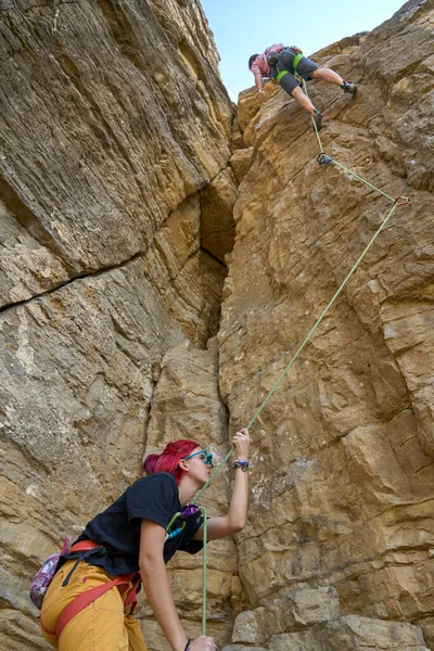 Teenage girl securing her climbing partner in a difficult rock climbing tour by a securing rope systemin Hessigheim, Baden-Wuerttemberg, Germany