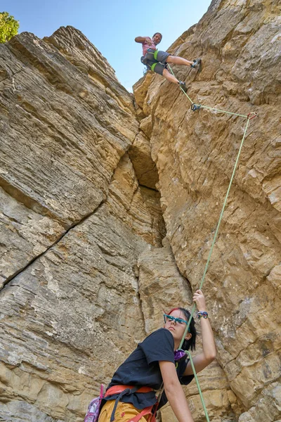 Teenage girl securing her climbing partner in a difficult rock climbing tour by a securing rope systemin Hessigheim, Baden-Wuerttemberg, Germany