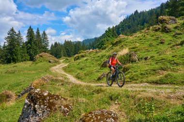 nice senior woman riding her electric mountain bike in the Bregenz Forest mountains near Hittisau, Vorarlberg Austria