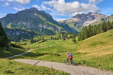 active senior woman, riding her electric mountain bike in the Arlberg mountain range near the famous village of Lech, Tirol, Austrian Alps