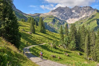 active senior woman, riding her electric mountain bike in the Arlberg mountain range near the famous village of Lech, Tirol, Austrian Alps