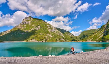 active senior woman, riding her electric mountain bike at Spuller Lake in the Arlberg area near the famous village of Lech, Tirol, Austrian Alps
