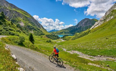 active senior woman, riding her electric mountain bike at Spuller Lake in the Arlberg area near the famous village of Lech, Tirol, Austrian Alps