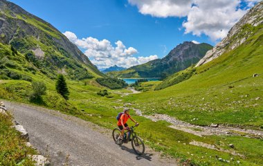 active senior woman, riding her electric mountain bike at Spuller Lake in the Arlberg area near the famous village of Lech, Tirol, Austrian Alps