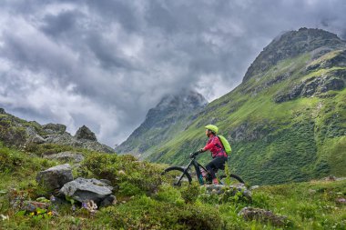 nice active senior woman riding her electric mountain bike in the Jamtal Valley, silvretta mountain range near Gaschurn, Tyrol, Austria